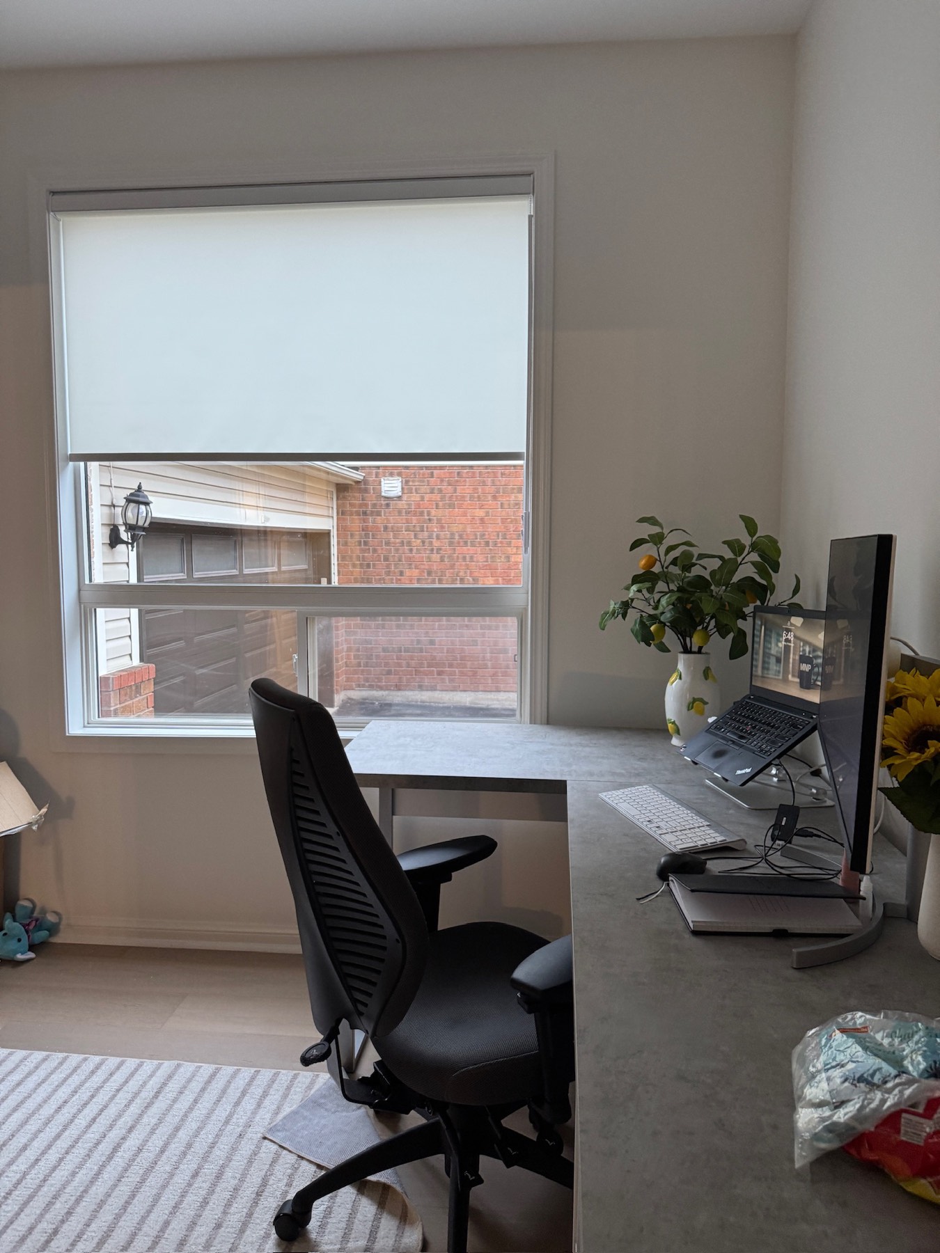 Roller shade half lowered over a home office window beside a desk